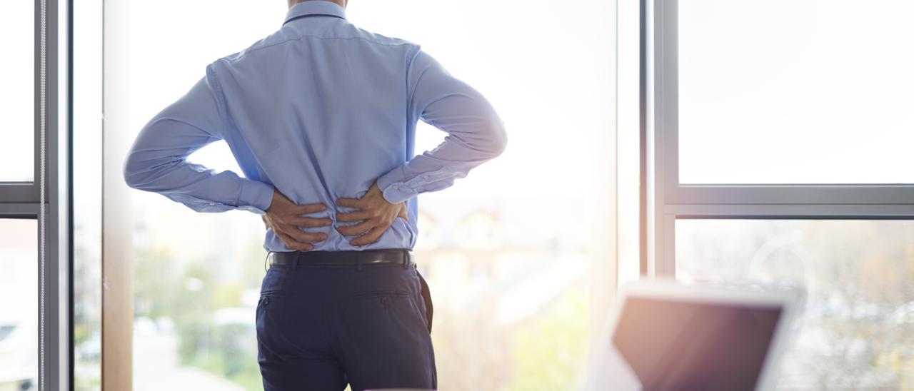 Un trabajador en una oficina con dolor de espalda.