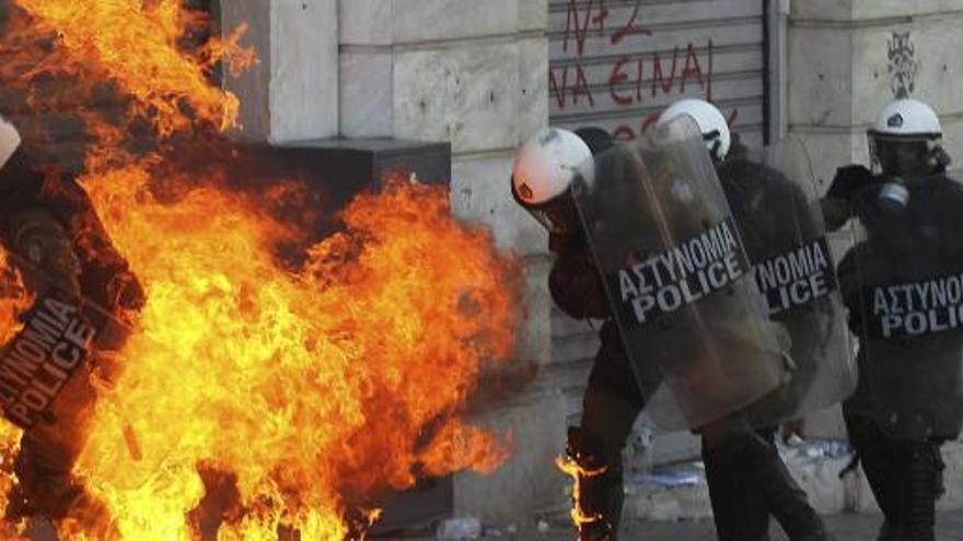 Policías antidisturbios se ven envueltos por las llamas de una bomba incendiaria.