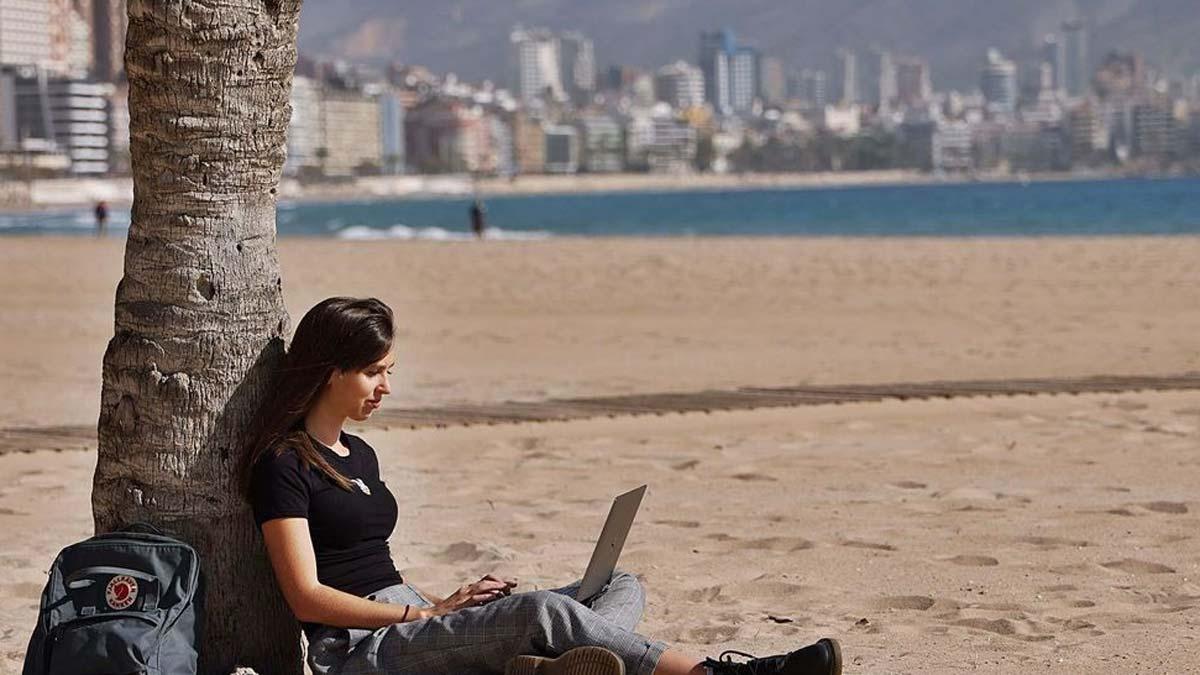 Una joven inglesa trabaja desde la playa de Benidorm con su ordenador, una de las posibilidades que tienen los «nómadas digitales».