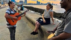 Cantantes cubanos cantan un bolero a una mujer en el malecón de La Habana, en Cuba