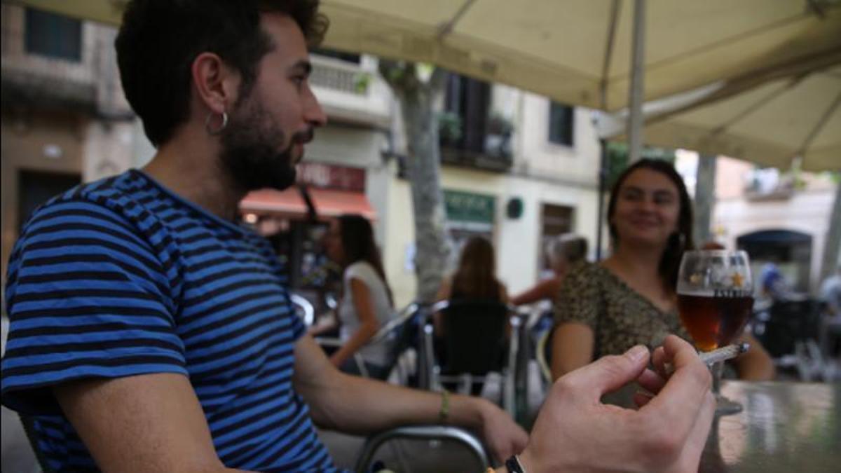 Un joven fuma en la terraza de un bar.