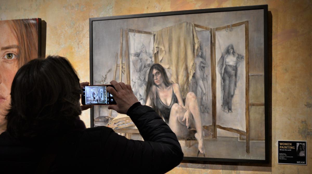 Una visitante junto al autorretrato de Carolina Souss pintado durante la cuarentena en su estudio. 
