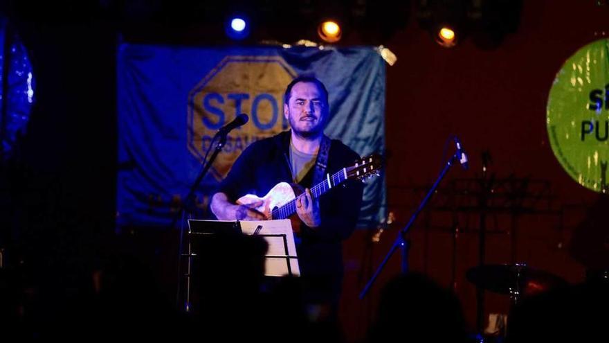 Ismael Serrano, en un momento del concierto, con una bandera contra los desahucios detrás.