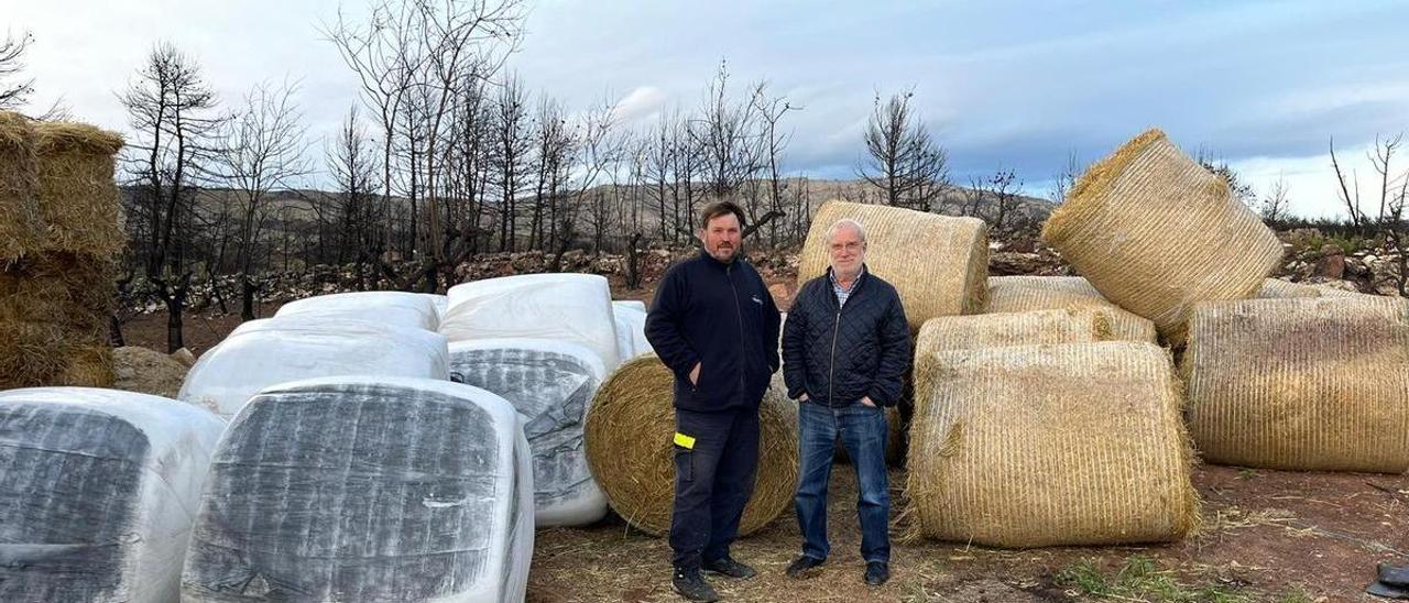 El ganadero Manolo Raimundo (i), de Torás, posa con el alcalde, Carlos del Río, delante de las balas de paja que ha recibido.