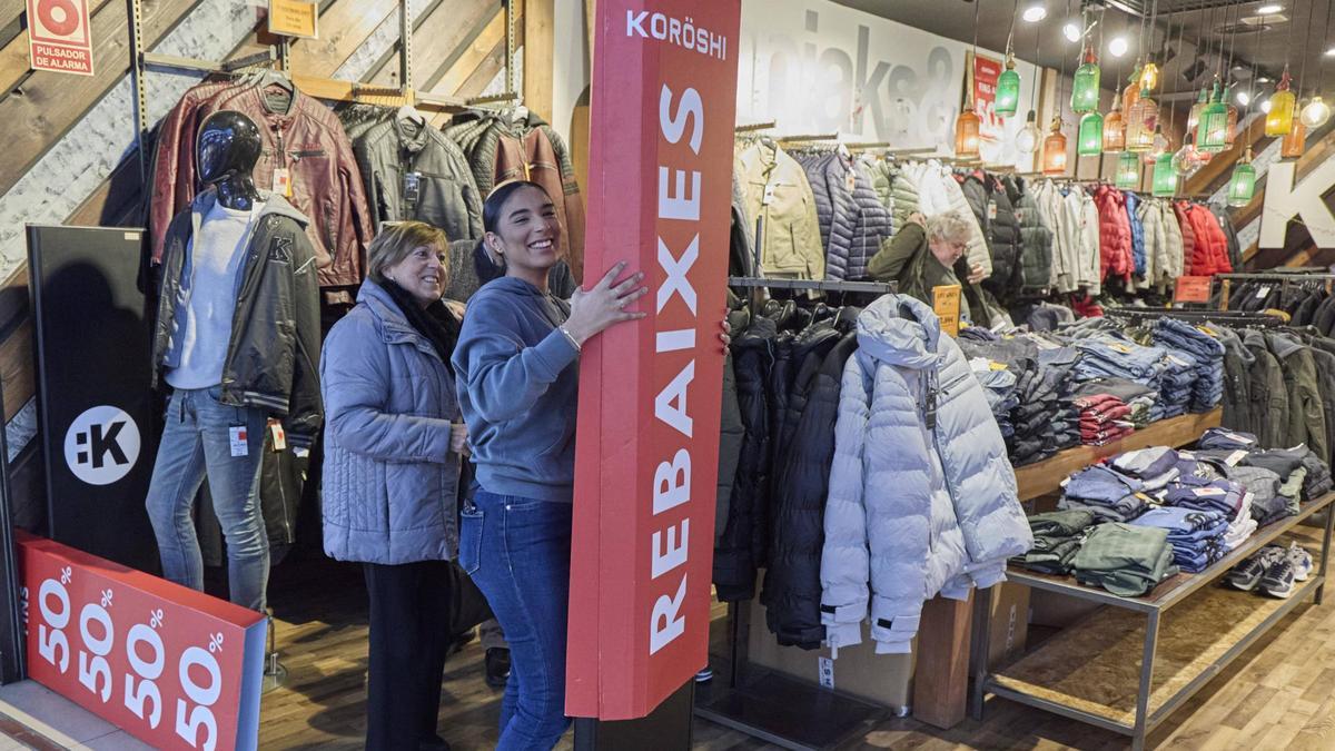 Una treballadora col·loca un cartell de rebaixes a una botiga de l'Espai Gironès.