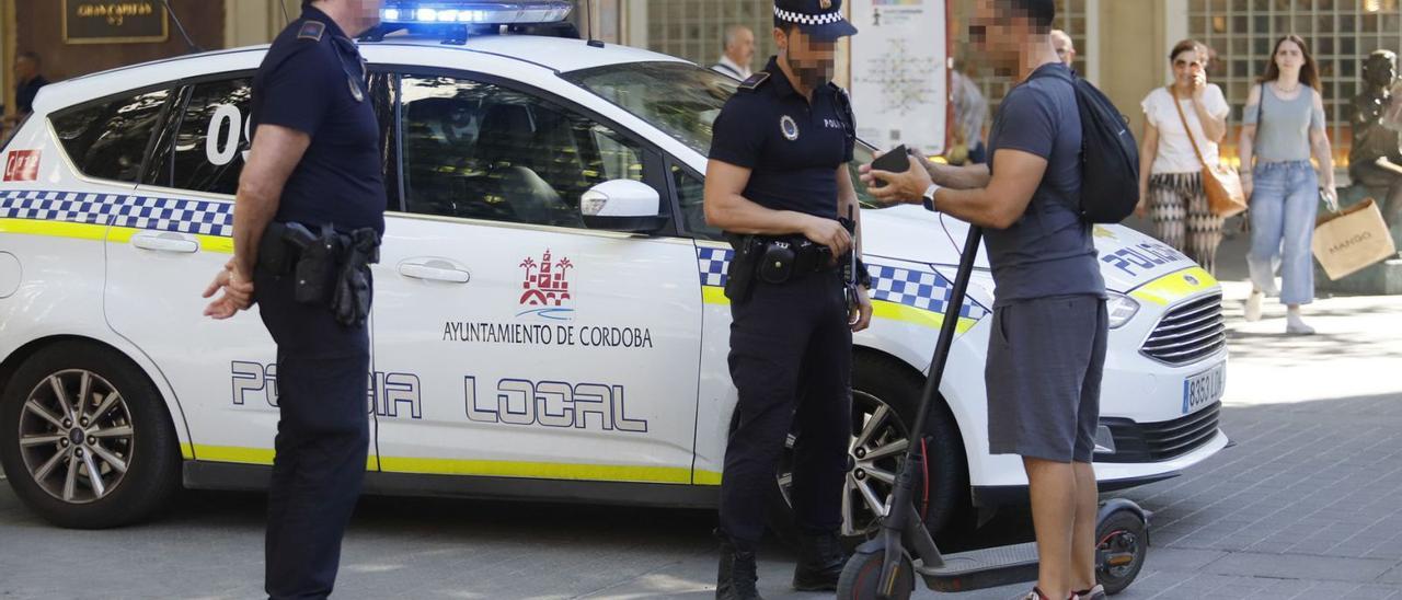 Dos agentes de la Policía Local comprueban la documentación del conductor de un patinete eléctrico en Córdoba.