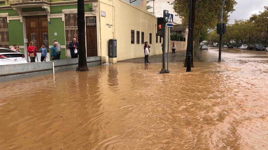 Vecinos de la calle de la Iglesia observan tras la compuerta la crecida del agua.