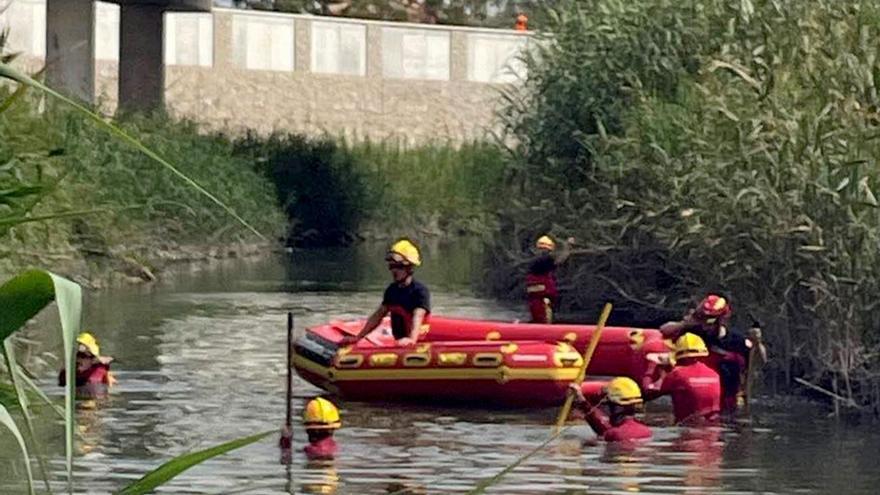 Momento en el que los bomberos trasladan el cadáver del menor ahogado en el Segura