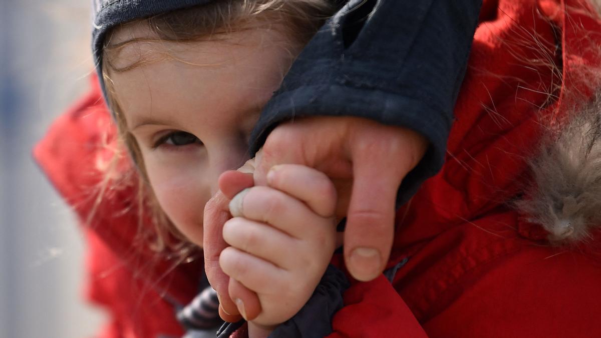 Una niña de la mano de su madre cruzando la frontera en Siret, Rumanía