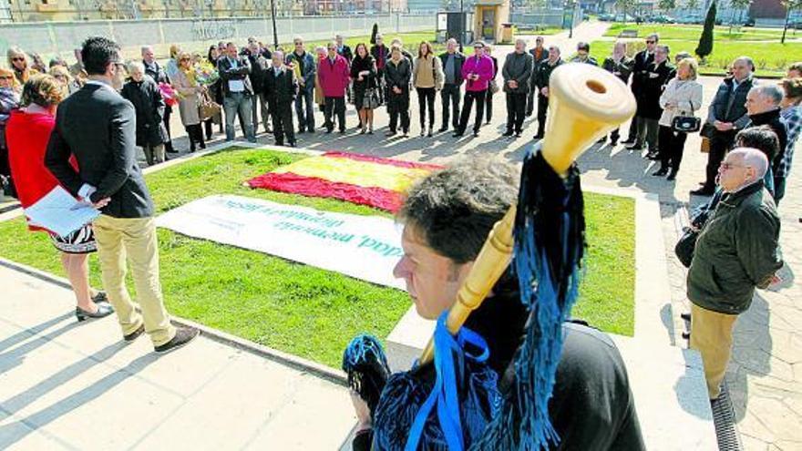 Un hombre deposita un ramo de flores ante el monumento en memoria de las víctimas del terrorismo mientras José Manuel Fernández toca una marcha fúnebre.