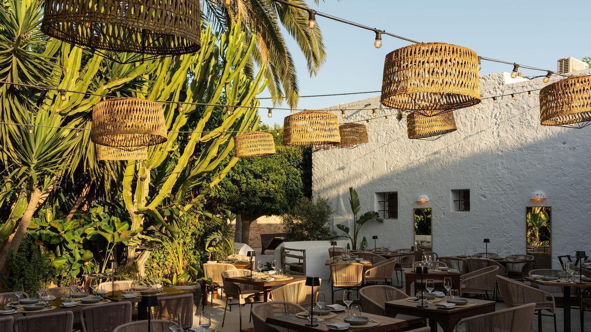 Las mesas están dispuestas con sobriedad en un espectacular patio con abundante vegetación.