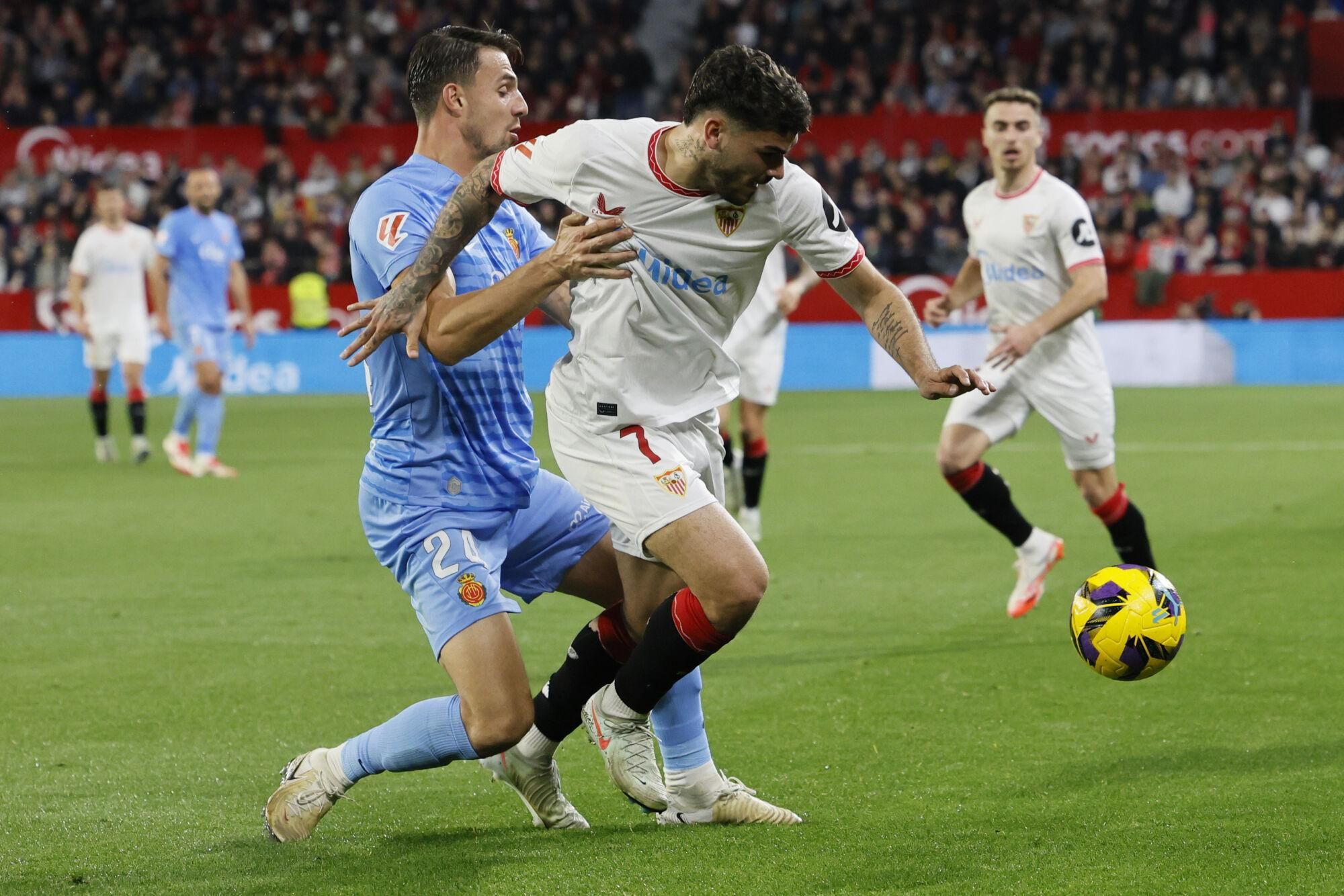 SEVILLA, 24/2/2025.- El delantero del Sevilla Isaac Romero (d) trata de escapar de Martin Valjent, del Mallorca, durante el partido de LaLiga de fútbol que Sevilla FC y RCD Mallorca disputan este lunes en el estadio Ramón Sánchez-Pizjuán. EFE/José Manuel Vidal