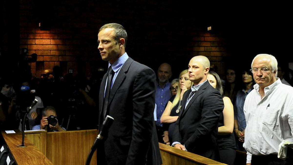 Oscar Pistorius, ante el Tribunal de la Magistratura de Pretoria, el lunes, observador por su hermano Carl (segundo por la derecha) y por su padre Henke Pistorius (derecha).