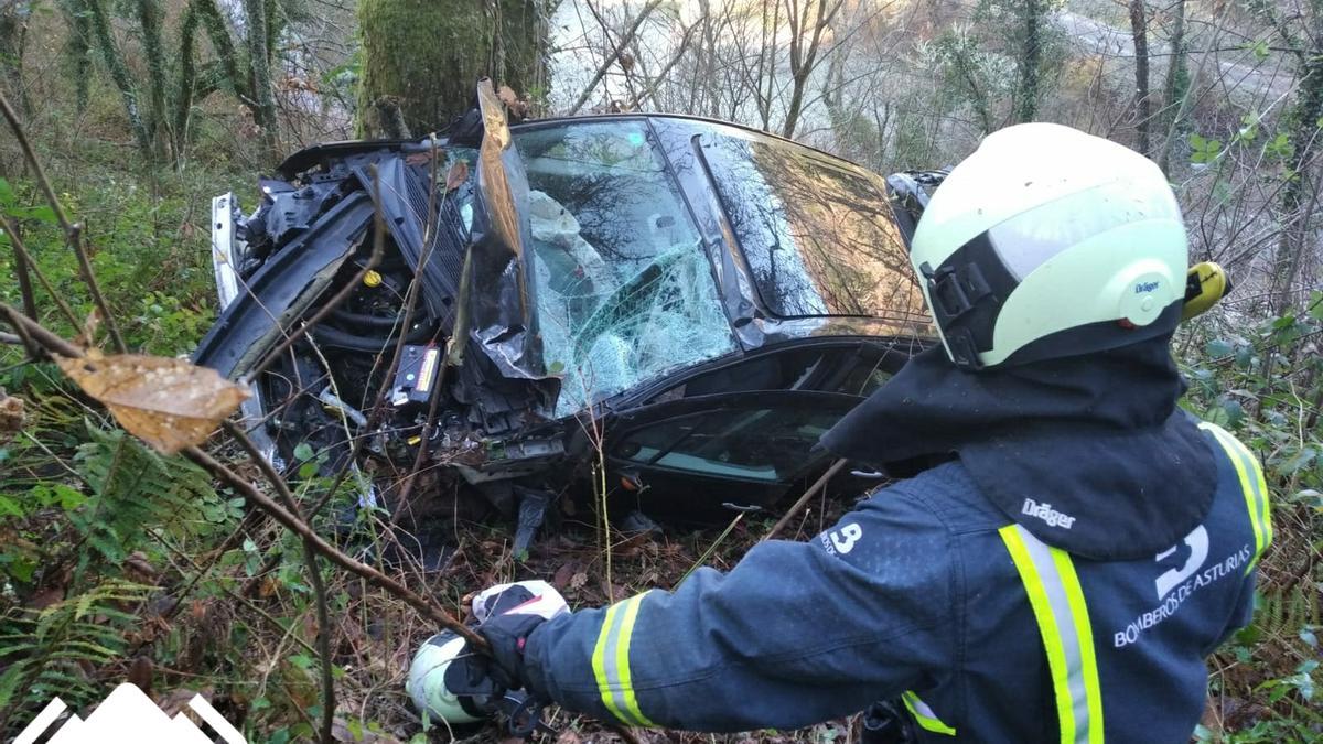 Un bombero junto al vehículo siniestrado.