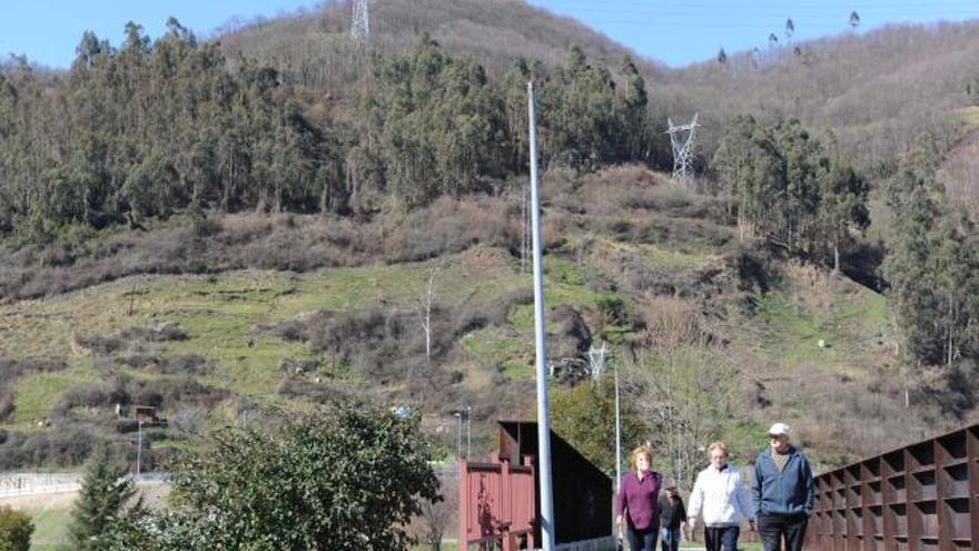 Varios vecinos caminando por el paseo de Figaredo junto a las farolas sin tulipas.