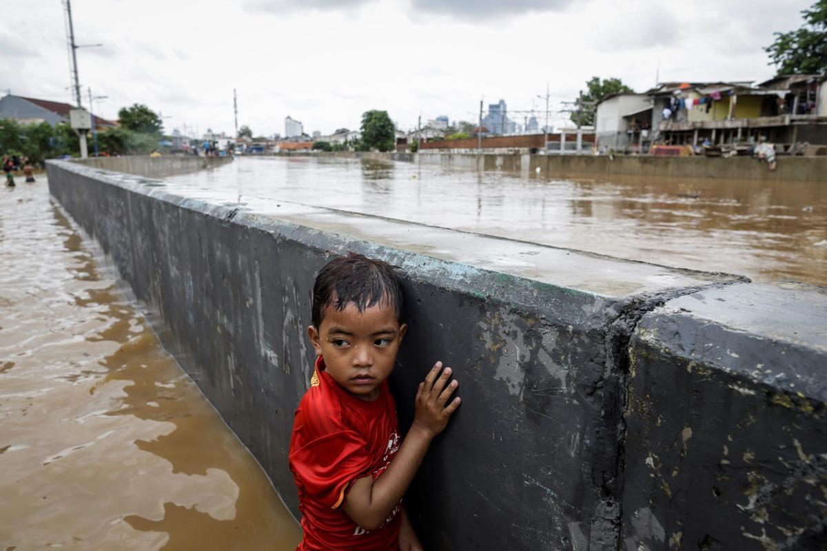 Un niño trata de salvarse en una de las frecuentes inundaciones de Yakarta