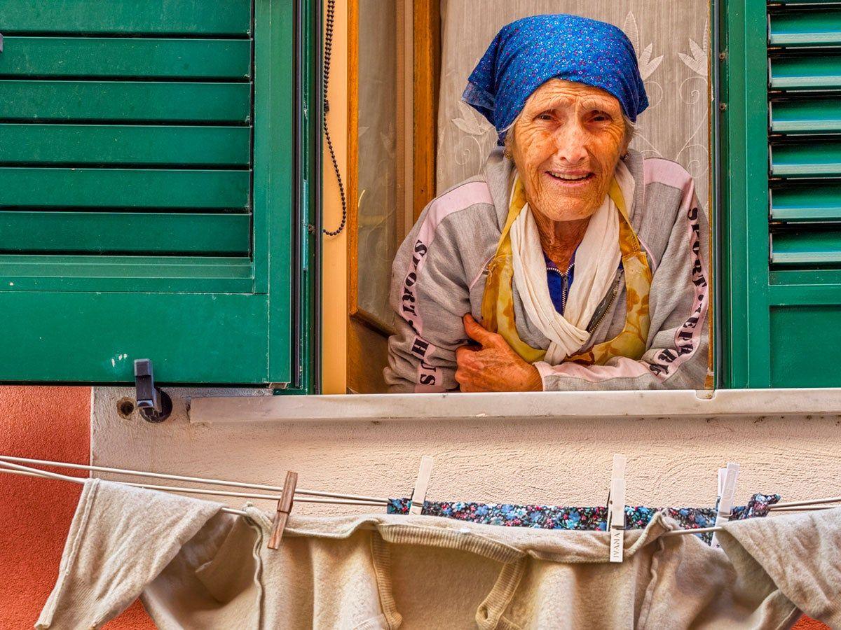 Mujer mirando por la ventana en la isla de Procida, en  Campania, Italia