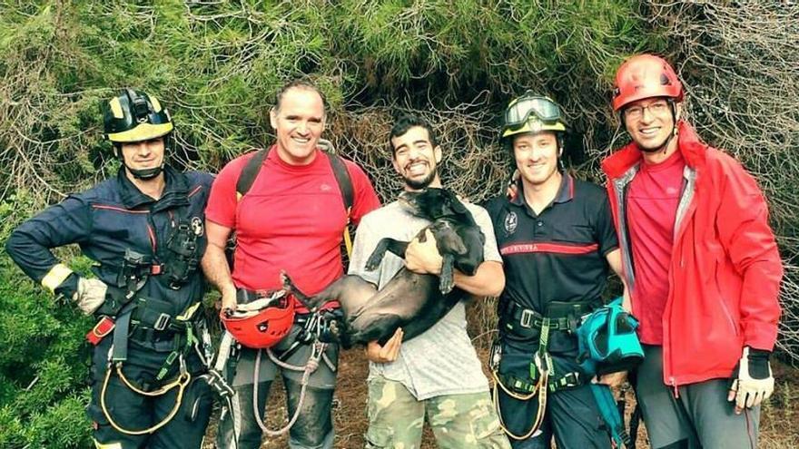 Kira con su dueño y los bomberos, justo después del rescate.