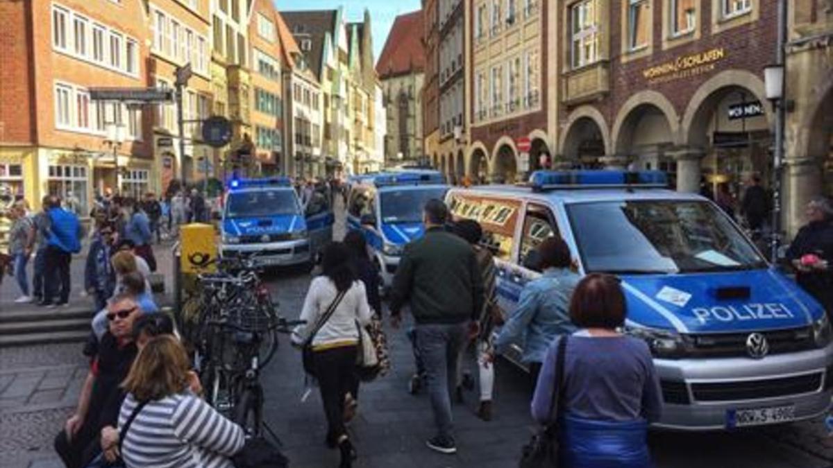 Vecinos y turistas circulan por el centro de Münster, entre furgonetas de la policía, tras el atropello de ayer.