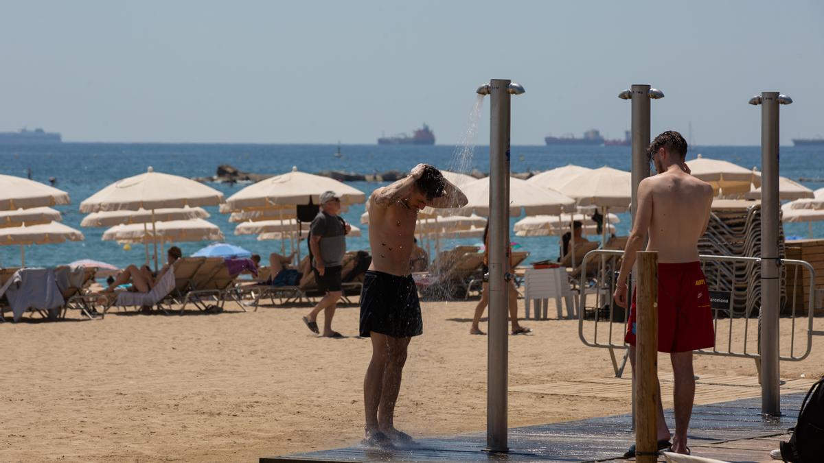 Varias personas se duchan en la playa de la Barceloneta, en Cataluña, en la ola de calor de julio del pasado 2022.