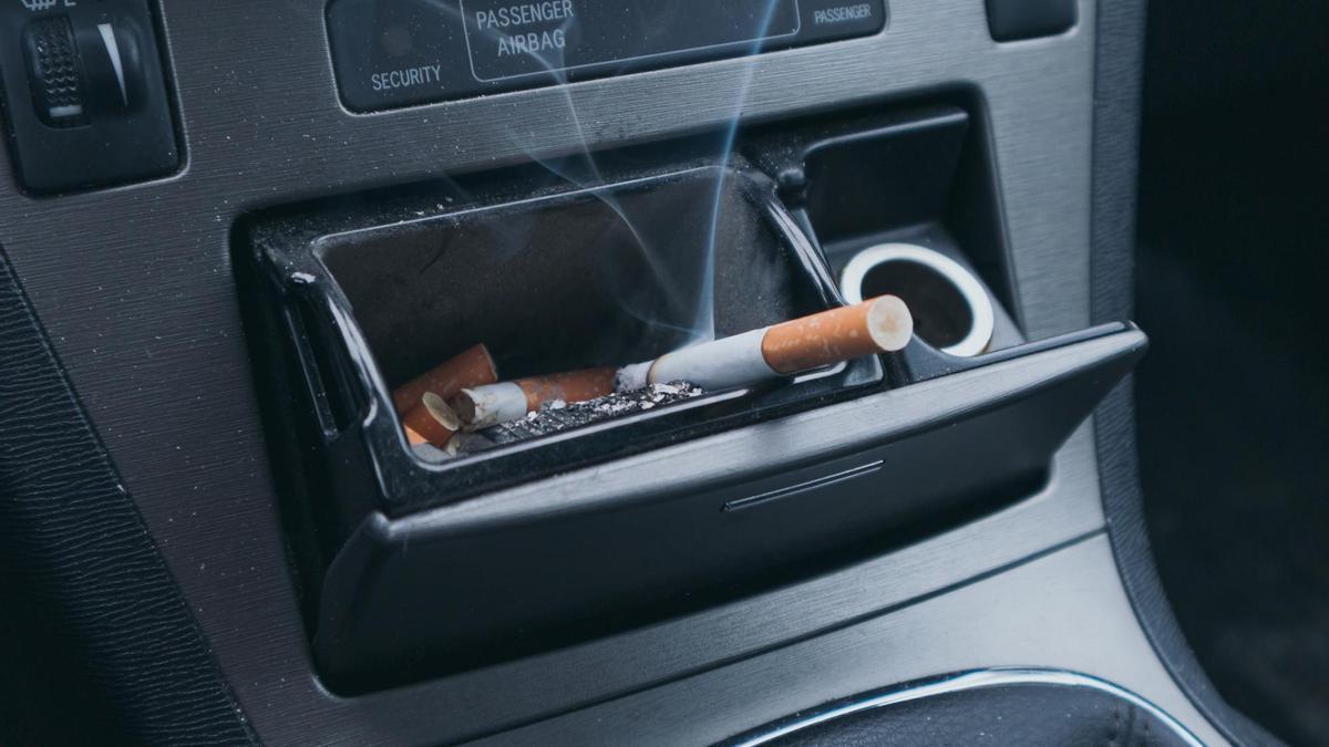 Un cigarro en el cenicero de un coche.