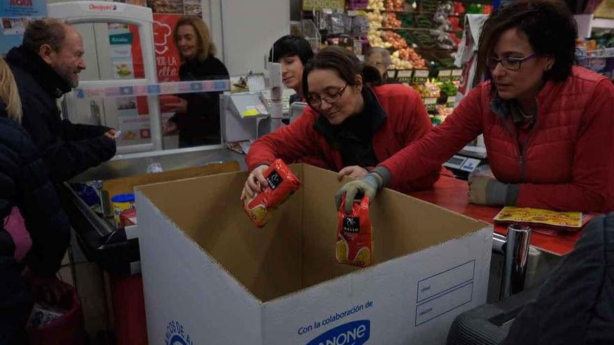 Dos mujeres entregan paquetes de pasta en uno de los cajones habilitados para la donación.