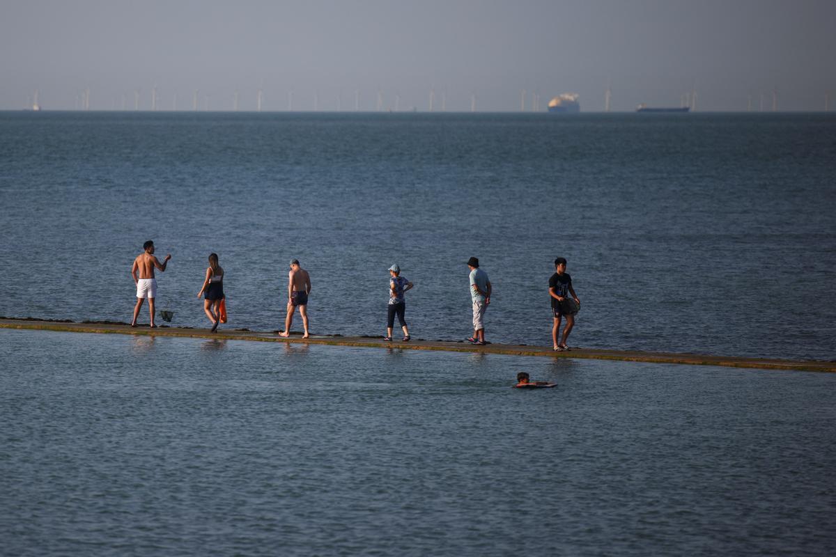 Un grupo de gente camina sobre el límite de una zona para baño en el mar en Margate, Gran Bretaña