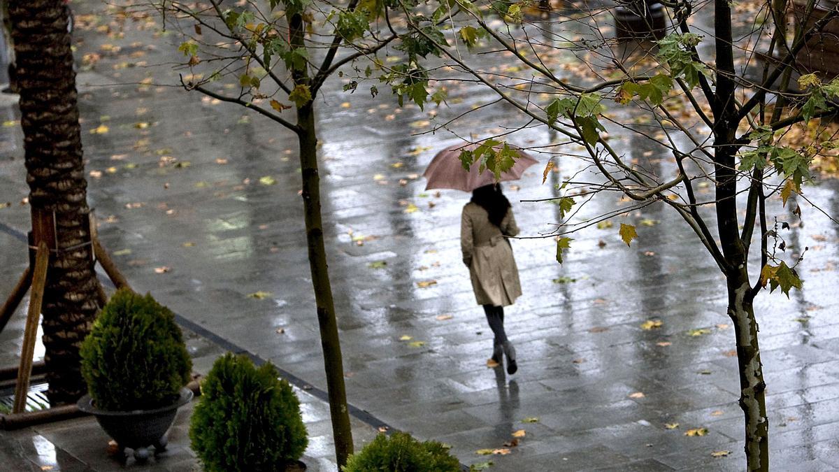 Una mujer camina bajo la lluvia.