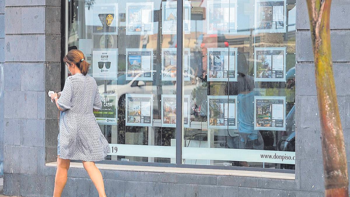 Una mujer pasa frente a una inmobiliaria.