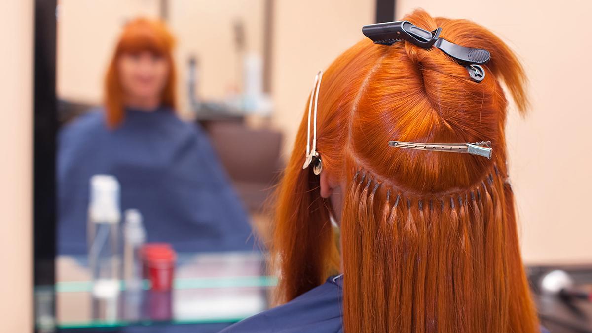 Una chica se coloca extensiones de pelo en un salón de belleza.