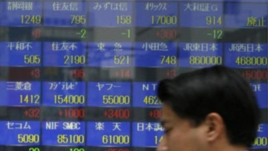 Un &quot;broker&quot; japonés examina un panel sobre el mercado de divisas.