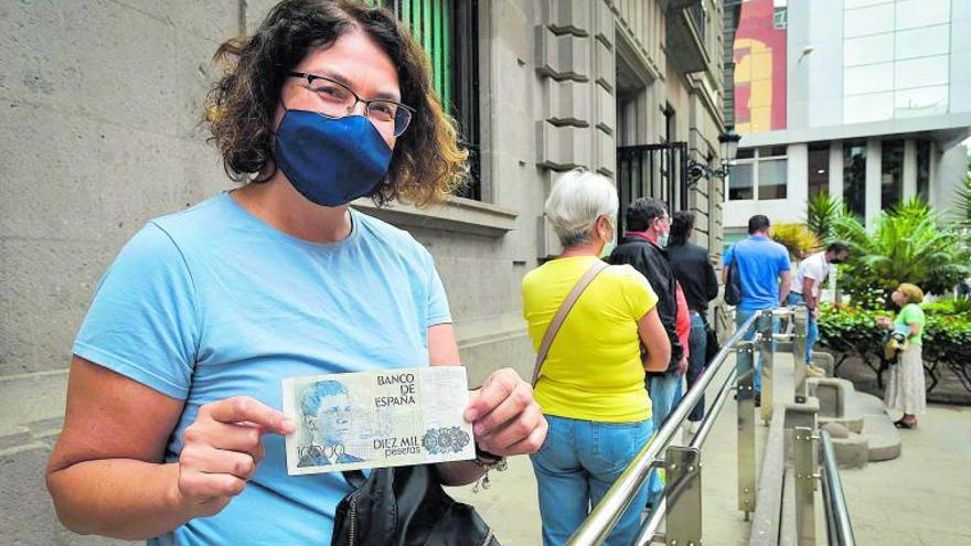 Montse Santana sostiene un billete de 10.000 pesetas, mientras hace cola para canjearlo por euros en el Banco de España.