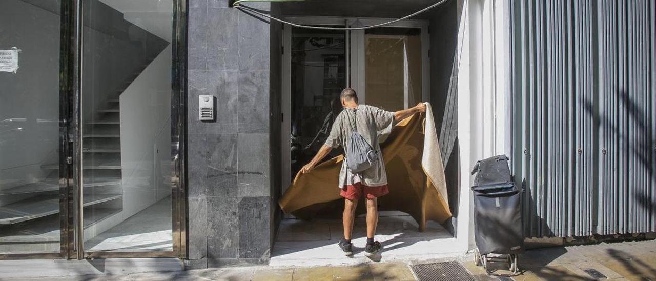 Una persona, sin hogar, recoge sus pertenencias en una conocida avenida de Alicante