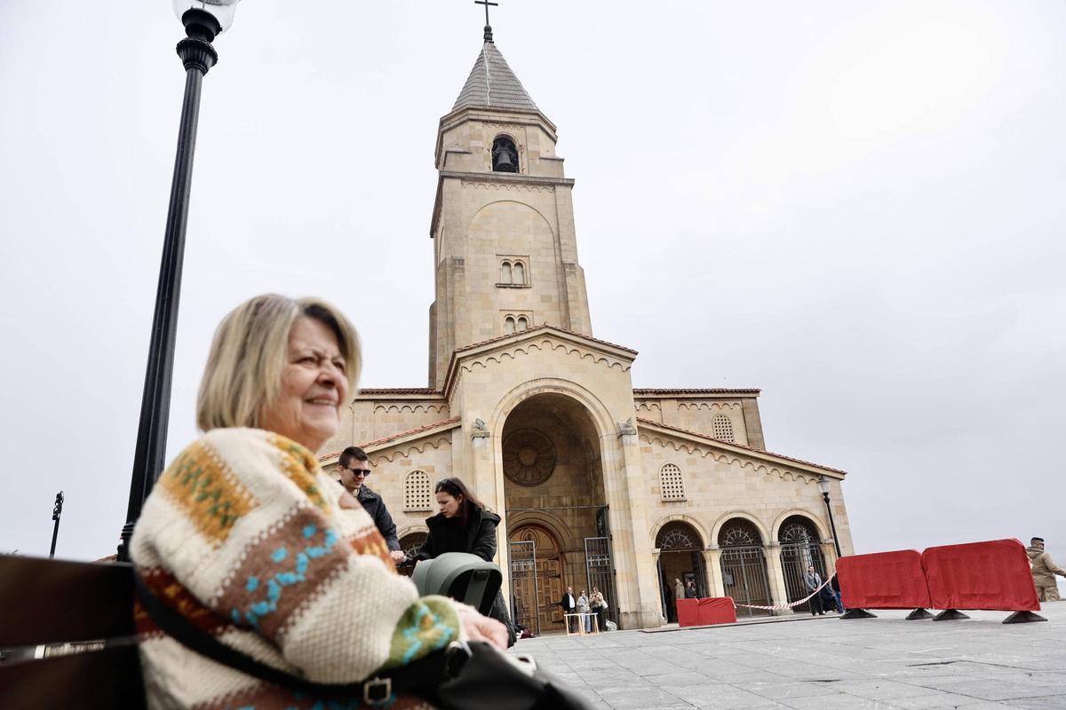 María García Suárez, sentada en el Campo Valdés, con la iglesia de San Pedro al fondo.