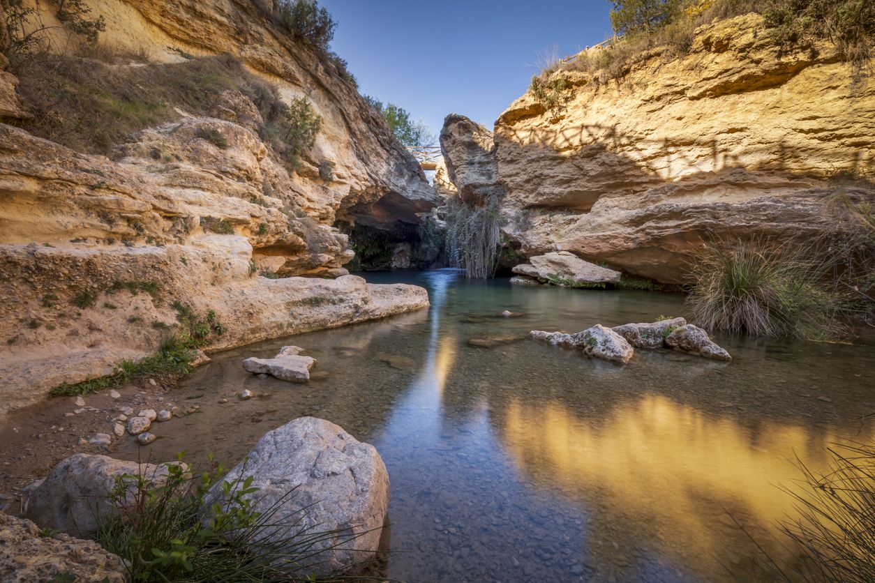 Cascada llamada Salto del Usero en Bullas, Murcia, España. Aguas azules y cristalinas bajo una cueva de roca amarilla