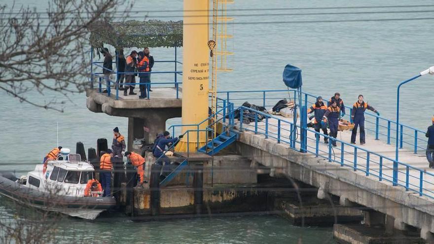 Operarios rusos transportan los cuerpos de los viajeros fallecidos.