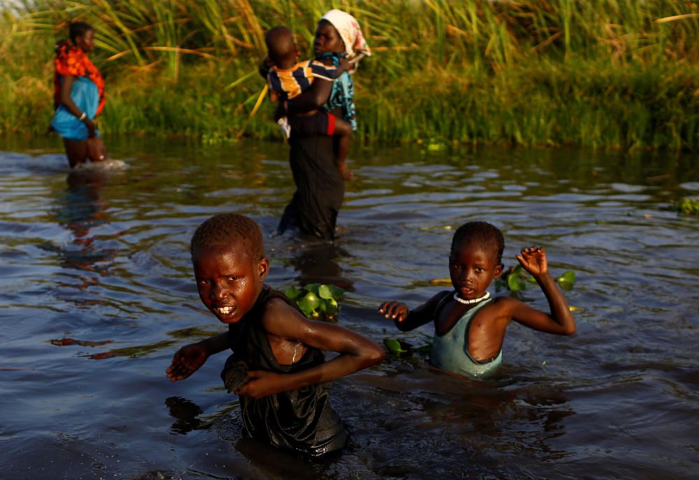 Unos niños cruzan un río para llegar a un carro de reparto de comida de Naciones Unidas en Sudán del Sur.