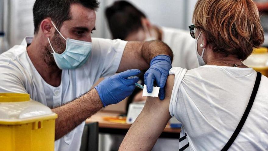 Un sanitario inocula una vacuna a una mujer.