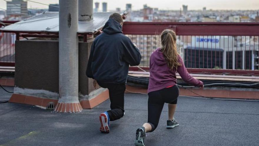 Dos personas hacen deporte en la azotea.