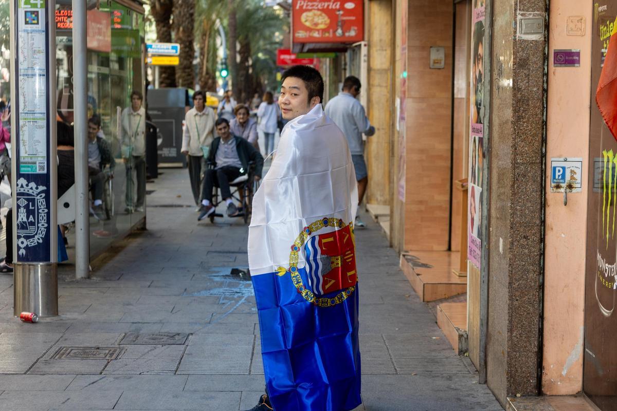 Fu Wang posa con una de las banderas alicantinas que vende en su tienda.