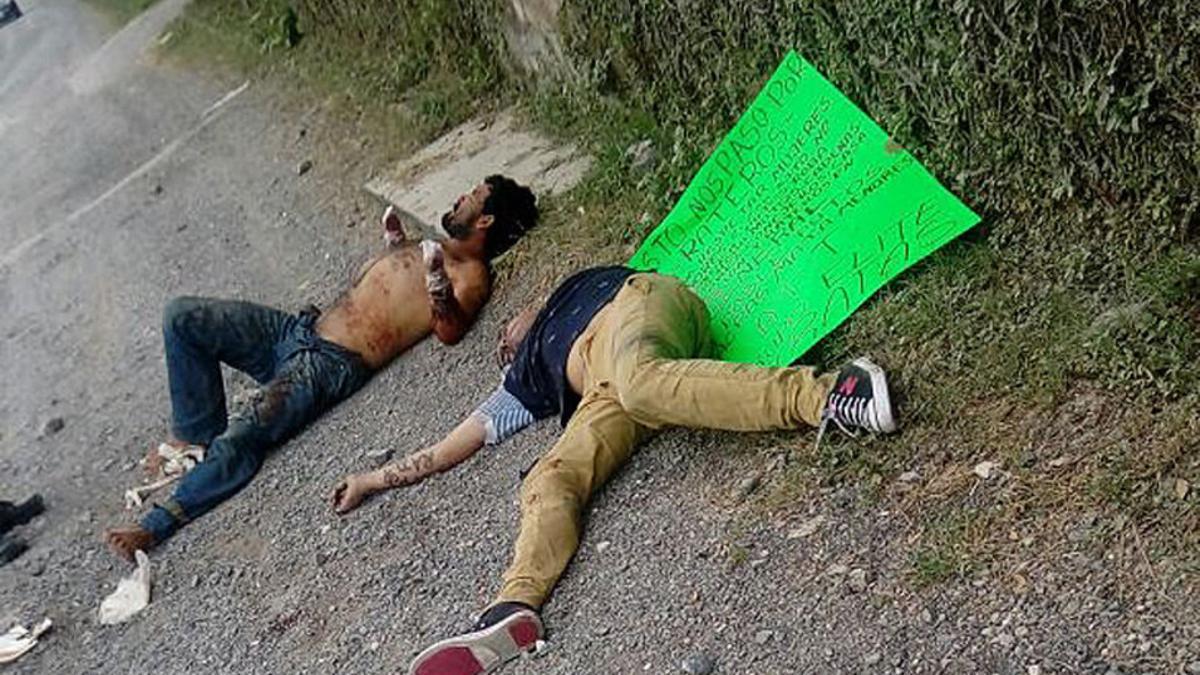 Dos de las víctimas en el suelo, junto a un cartel que les acusa de ladrones, firmado por un grupo de justicieros, este lunes en Guadalajara (México).