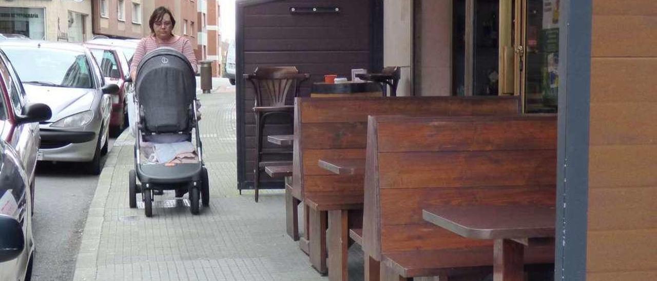 Inés Redondo, ayer, pasando junto a una terraza con una silla de bebé, en la Pola.