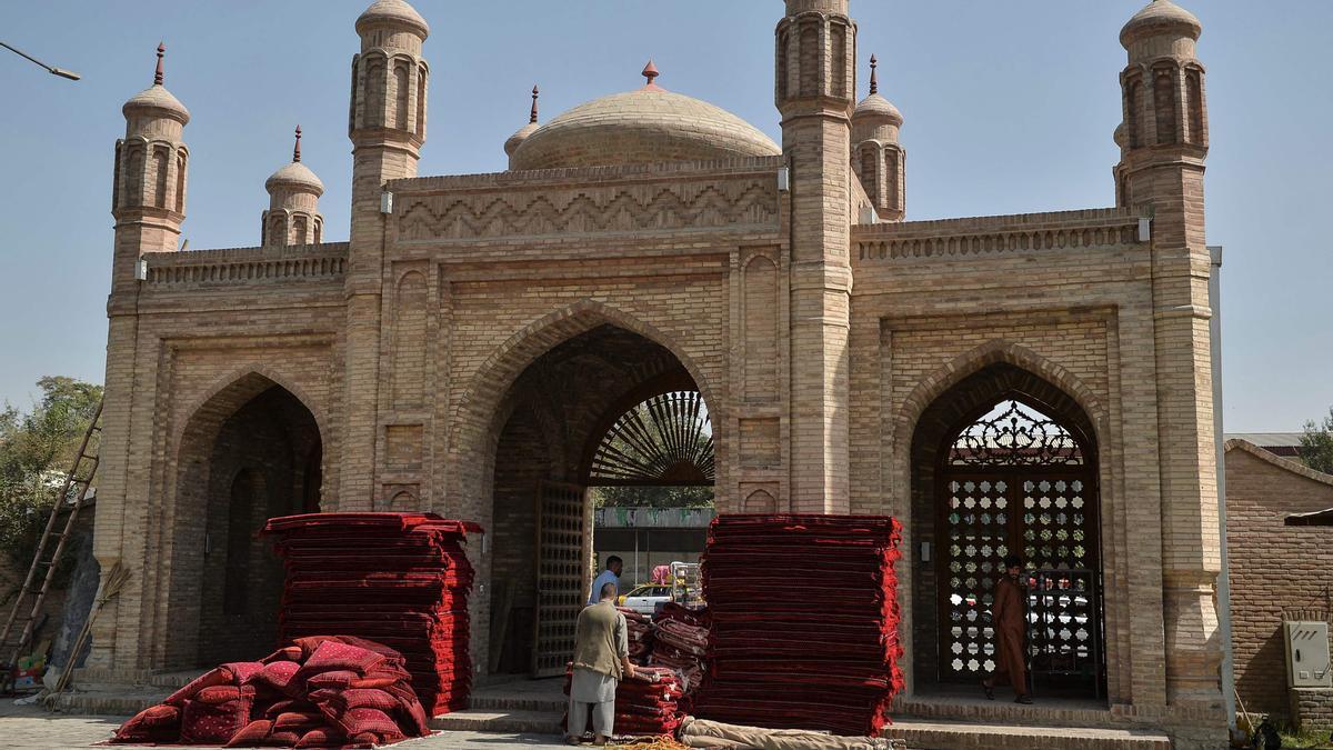 Varios trabajadores colocan almohadas y cojines a la entrada de la mequita de Eid Gah para los rezos por las víctimas en el atentado del domingo.
