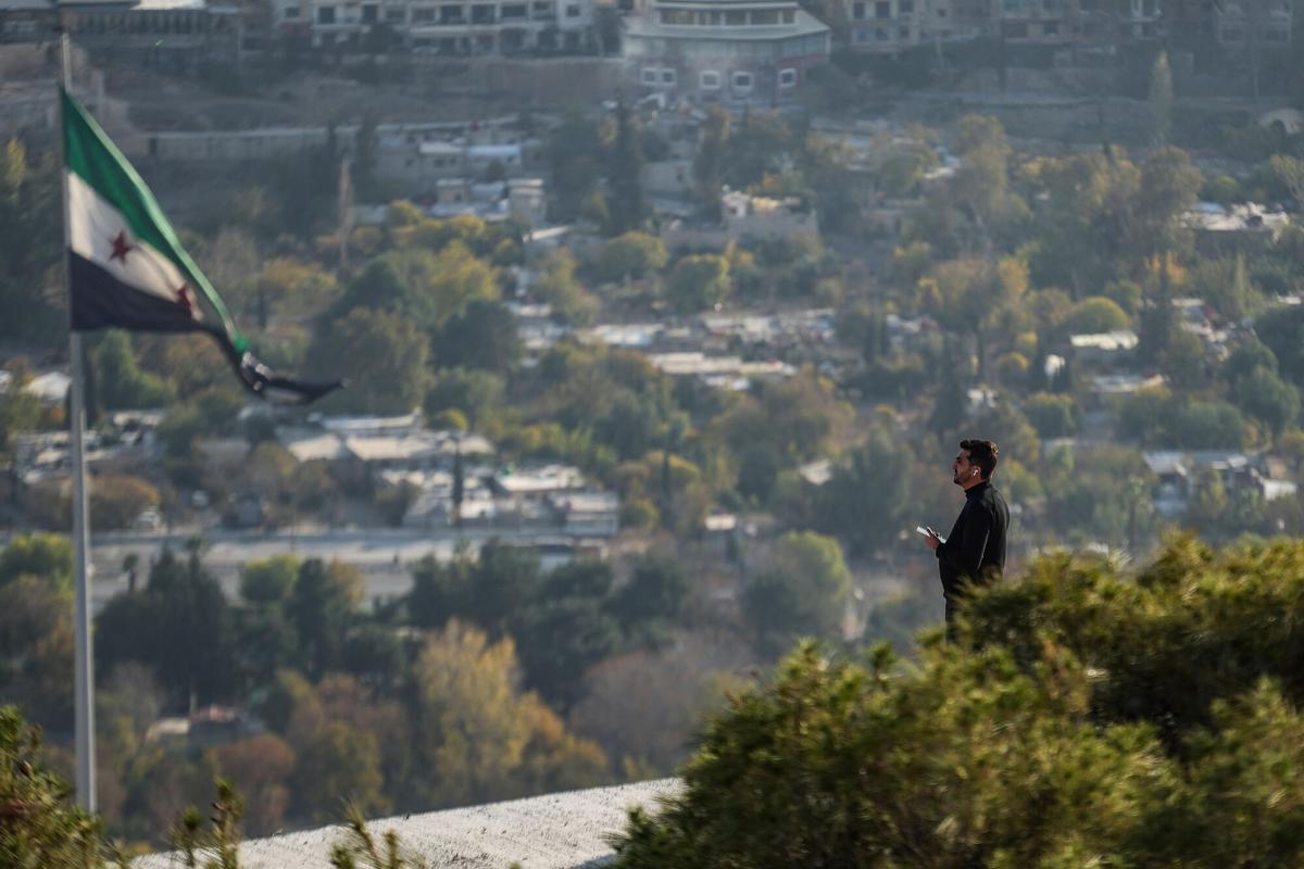 Un hombre frente a una bandera siria en una zona elevada de Damasco, este viernes.