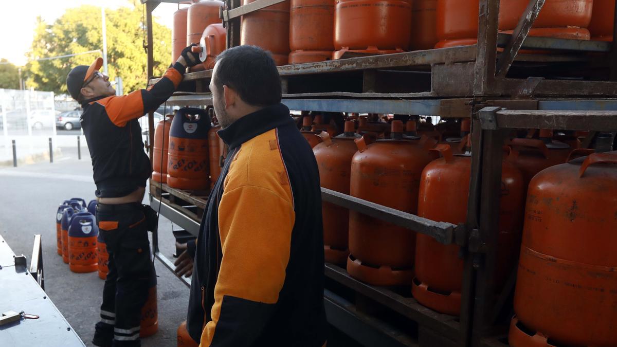 Operarios reponiendo bombonas de gas en una gasolinera.