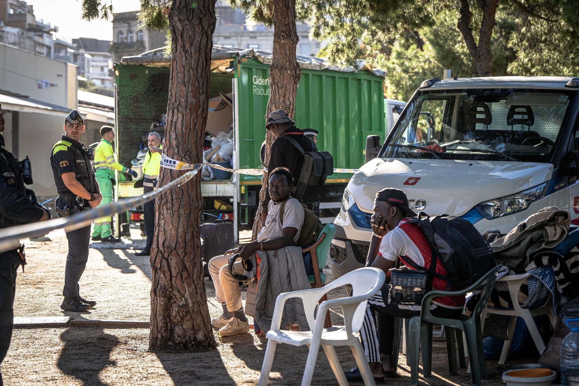 Agentes de la Guardia Urbana y trabajadores de la limpieza junto a algunos de los desalojados que acampaban en el parque de Joan Miró, en Barcelona.