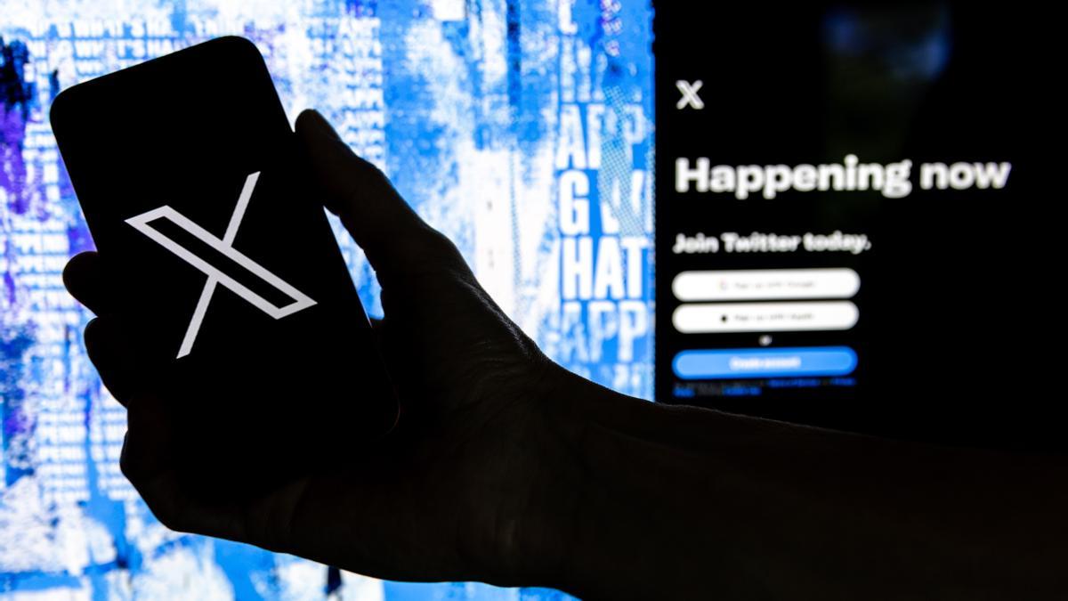Fotografía de archivo que muestra un usuario mientras sostiene un teléfono móvil que muestra el logotipo 'X' frente a la página principal de Twitter, el 28 de julio de 2023 en Los Ángeles, California (EE.UU.). EFE/EPA/ETIENNE LAURENT