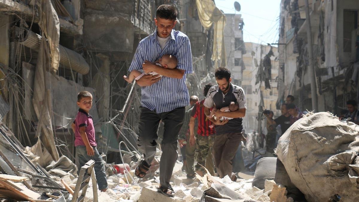 Hombres sirios llevan bebés a través de los escombros de edificios destruidos tras el ataque aéreo en el barrio de Salihin, controlado por los rebeldes en la ciudad norteña de Alepo, el 11 de septiembre de 2016.