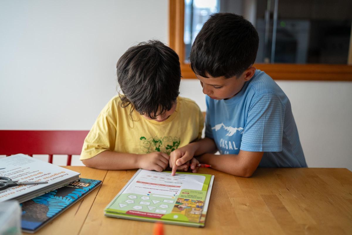 Dos hermanos de 9 y 6 años hacen deberes en casa durante las vacaciones de verano.