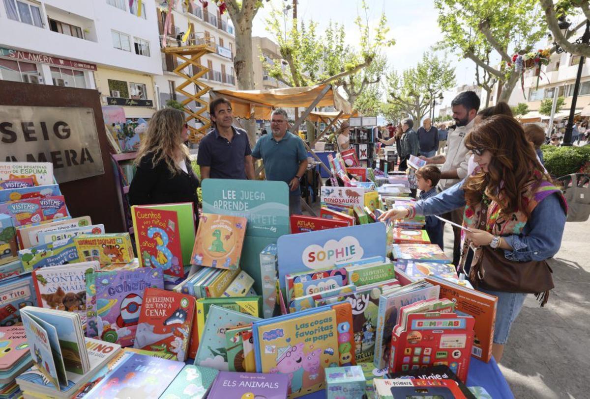 Varios visitantes curiosean entre los libros expuestos.